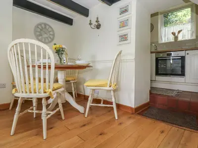 a dining room with a table and chairs and a fireplace at Driftwood Cottage in St Austell