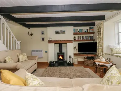 a living room with a couch and a fire place at Driftwood Cottage in St Austell