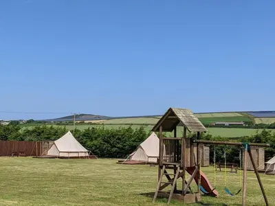 a playground with tents and a swing set at I do glamping penhallow campsite Ltd in Truro