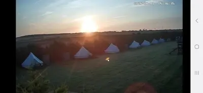 a group of tents in a field at sunset at I do glamping penhallow campsite Ltd in Truro