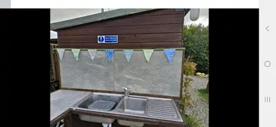 a sink in front of a building with a sign on it at I do glamping penhallow campsite Ltd in Truro