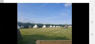 a field with a group of tents in the distance at I do glamping penhallow campsite Ltd in Truro