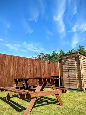 a wooden picnic table next to a wooden fence at I do glamping penhallow campsite Ltd in Truro