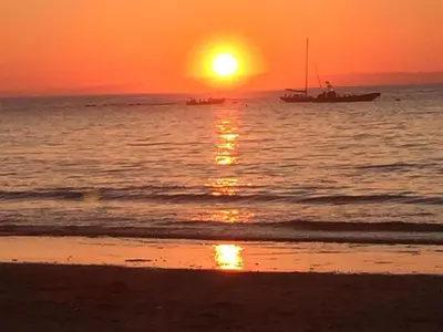 a boat in the ocean at sunset with a beach at Seafell in Forrabury