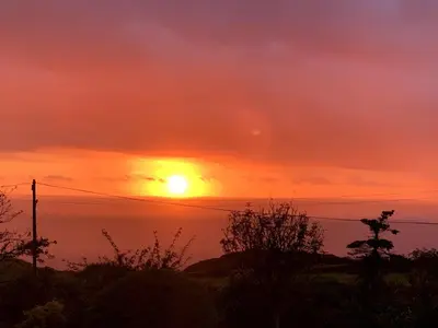 a sunset over the ocean with the sun in the sky at Seafell in Forrabury