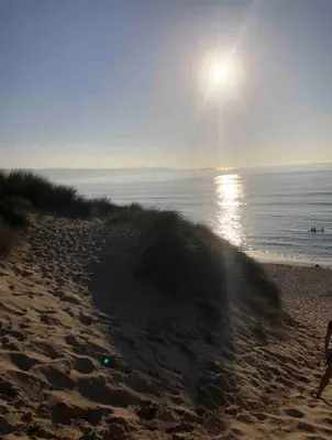 a beach with the sun rising over the water at Cornwall Shepherds Hut - Hot Tub & Cosy Log Burner in Saint Day