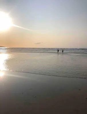 two people walking in the water on the beach at Cornwall Shepherds Hut - Hot Tub & Cosy Log Burner in Saint Day