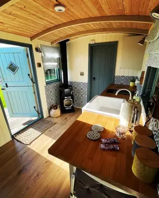 a kitchen with a sink and a stove in a room at Cornwall Shepherds Hut - Hot Tub & Cosy Log Burner in Saint Day