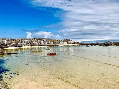 a beach with a red boat in the water at Heart of St Ives with parking - 2 bedrooms in St Ives