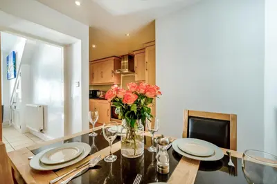 a dining room with a table with a vase of flowers at 3 Bed in Polperro oc-h34100 in Polperro