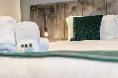 a bed with a green pillow and towels on it at 4 Bed in Winnards Perch oc-w34023 in Saint Columb Major