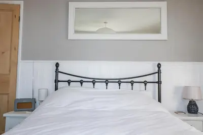 a bedroom with a white bed with a picture on the wall at Rosedale in St Ives