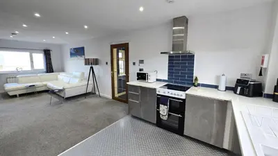 a kitchen with a stove top oven next to a living room at Stepping Stones in Perranporth