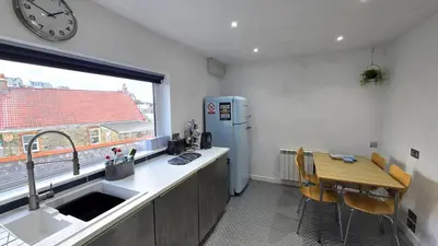 a kitchen with a sink and a refrigerator and a window at Stepping Stones in Perranporth