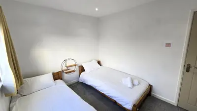 two beds in a small room with white sheets at Stepping Stones in Perranporth