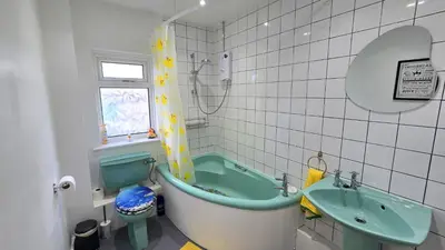 a bathroom with a green tub and a sink at Stepping Stones in Perranporth