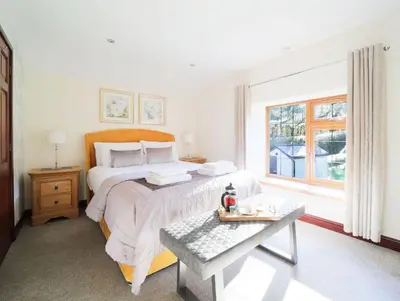 a white bedroom with a bed and a window at Foxglove Cottage in Liskeard