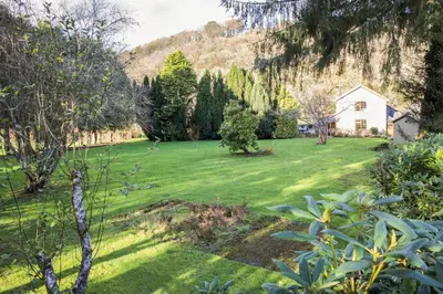 a green yard with a house in the background at Foxglove Cottage in Liskeard