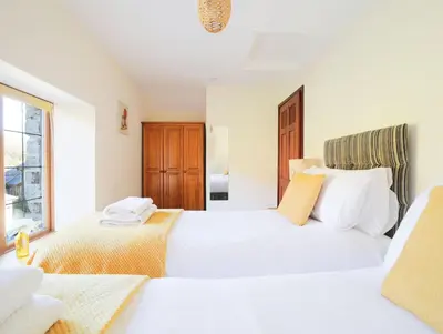 a bedroom with two beds and a window at Foxglove Cottage in Liskeard