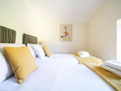 a white bedroom with two beds and a window at Foxglove Cottage in Liskeard