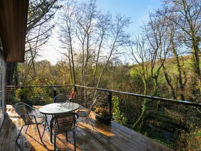 a patio with a table and chairs on a deck at 6 Stonerush Valley in Looe