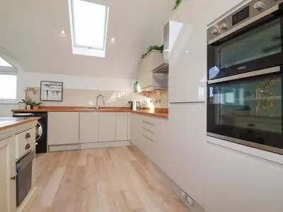 a kitchen with white cabinets and a large window at 33 Fordh Tobmen in St. Agnes