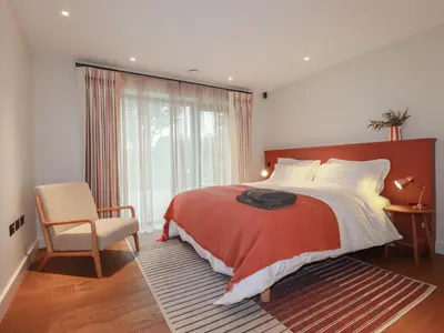 a bedroom with a bed and a chair and a window at Harberton in Wadebridge