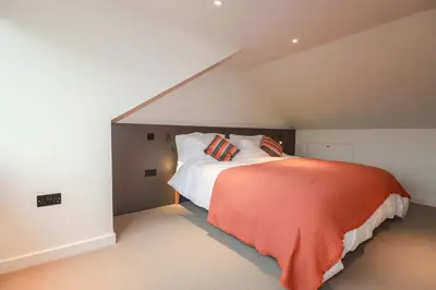 a attic bedroom with a bed with an orange blanket at Harberton in Wadebridge