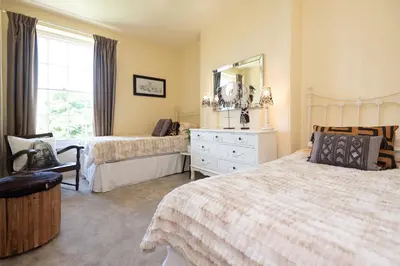 a bedroom with two beds and a mirror at The Old Vicarage in Wadebridge