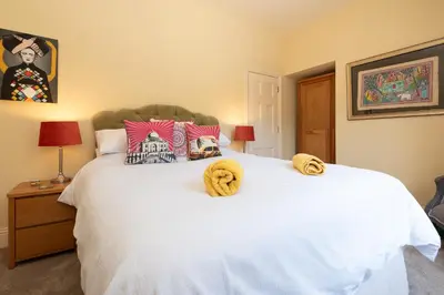 a bedroom with a white bed with yellow towels on it at The Old Vicarage in Wadebridge