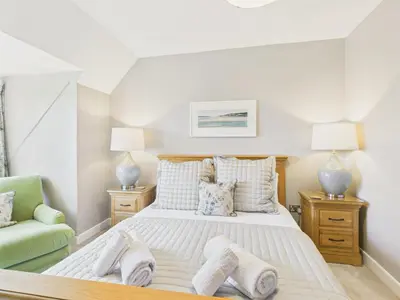 a bedroom with a bed and a green chair at Wyvern – Beautiful & Spacious 4-Bedroom Home with Parking & Gardens in Falmouth