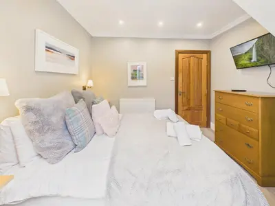 a bedroom with a white bed and a dresser at Wyvern – Beautiful & Spacious 4-Bedroom Home with Parking & Gardens in Falmouth