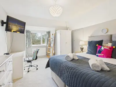 a bedroom with a bed and a desk and a television at Wyvern – Beautiful & Spacious 4-Bedroom Home with Parking & Gardens in Falmouth