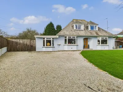 a white house with a fence and a gravel driveway at Wyvern – Beautiful & Spacious 4-Bedroom Home with Parking & Gardens in Falmouth