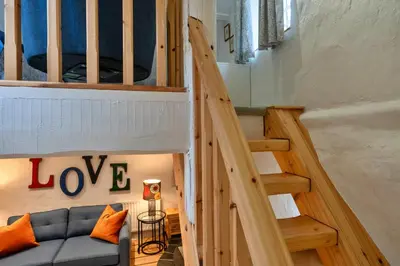 a living room with a couch and a staircase at Finest Retreats - Spray Barn in Saint Ervan