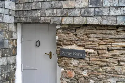 a brick building with a sign next to a door at Finest Retreats - Spray Barn in Saint Ervan