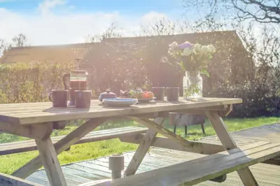 a wooden picnic table with a vase of flowers on it at 1 Bed in Widegates oc-p34230 in Sheviock