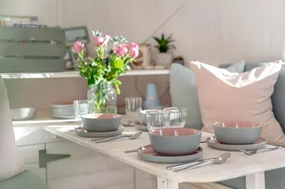 a table with bowls and plates and a vase of flowers at 1 Bed in Widegates oc-c34232 in Sheviock