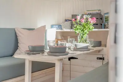 a table with plates and glasses and a vase of flowers at 1 Bed in Widegates oc-c34232 in Sheviock