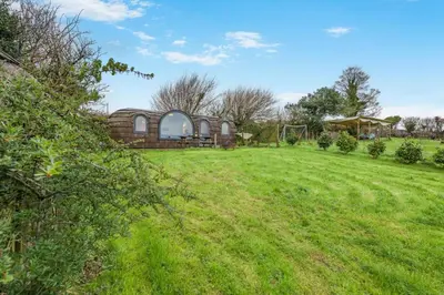 a large grass field with a building in the background at 1 Bed in Widegates oc-d34231 in Sheviock