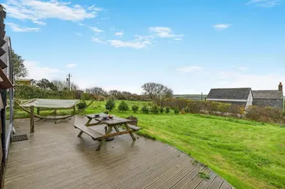 a wooden deck with a picnic table and a hammock at 1 Bed in Widegates oc-d34231 in Sheviock
