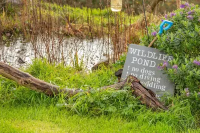a sign sitting in the grass next to a pond at 1 Bed in Widegates oc-j34234 in Sheviock