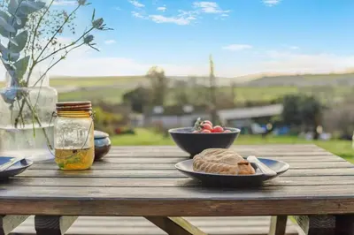 a wooden table with plates of food and a bowl of fruit at 1 Bed in Widegates oc-p34236 in Sheviock