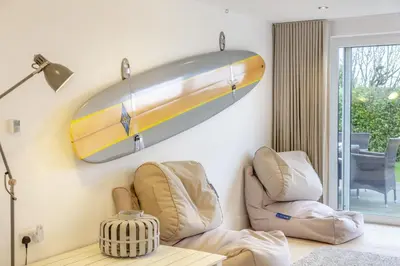 a surfboard hanging on a wall next to two chairs at 4 Bed in Widemouth Bay oc-s34119 in Widemouth Bay