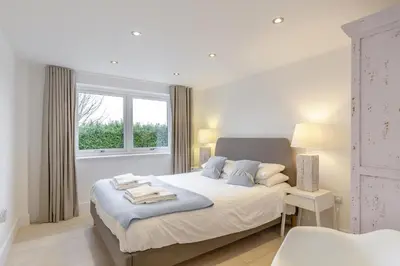 a white bedroom with a bed and a window at 4 Bed in Widemouth Bay oc-s34119 in Widemouth Bay