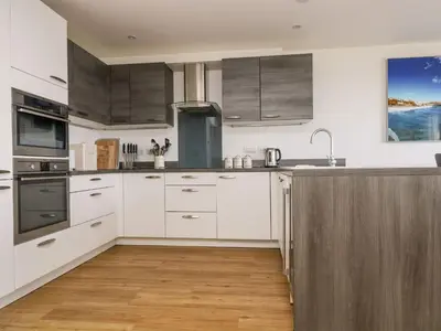 a kitchen with white cabinets and stainless steel appliances at Praa Waves in Penzance