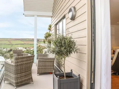 a balcony with wicker chairs and a plant at Praa Waves in Penzance