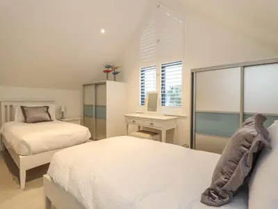 a bedroom with two beds and a desk and a window at Praa Waves in Penzance