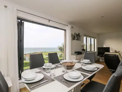 a dining room with a table and a large window at Praa Waves in Penzance
