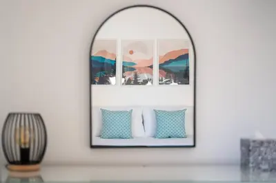 a mirror above a table with pillows on it at Peaceful cottage near beaches - Bickland View in Falmouth